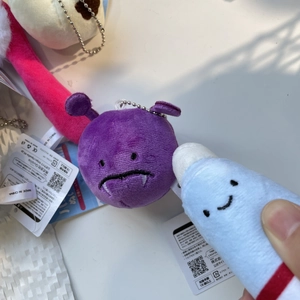 Close-up of cute purple monster and blue smiling plush pendants with metal chains