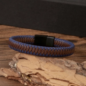 Detail of woven blue and brown leather bracelet with black magnetic clasp on bark