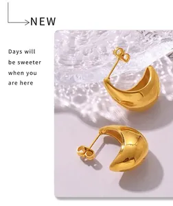 Macro shot of 18k gold plated C-shaped crescent earrings on a textured glass surface