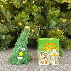 Albero di Natale elettrico di peluche con campanello e confezione regalo su sfondo festivo