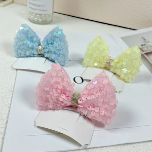 Detail of blue, yellow, and pink sequined mesh bow hair clips on white card display