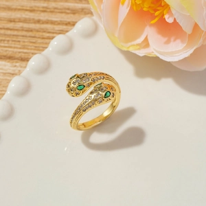 Detail of snake bypass ring with cubic zirconia paving and emerald green eyes