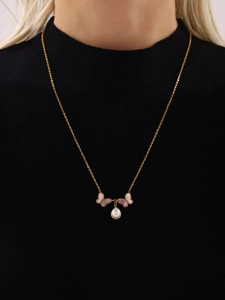 Gros plan d'un collier doré avec pendentifs papillon en nacre et perle sur un mannequin