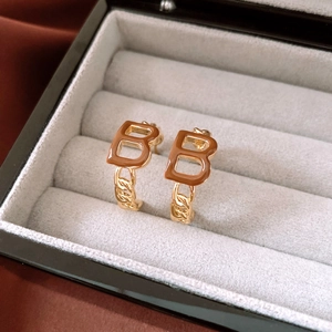 Detail view of gold-plated B-shaped earrings with brown enamel and chain link accents