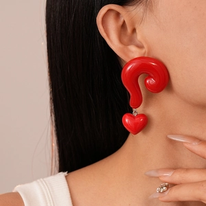 Close-up of vibrant red question mark and heart resin earrings worn by a model