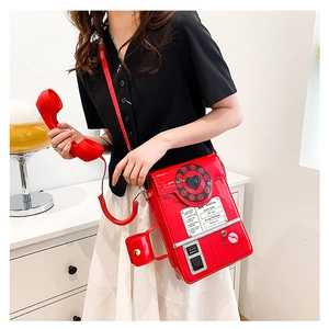 Detail of red telephone crossbody bag with heart dial and retro Best Hotline text