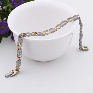 Dettaglio del bracciale con maglie a cuore in acciaio bicolore su una ciotola di ceramica