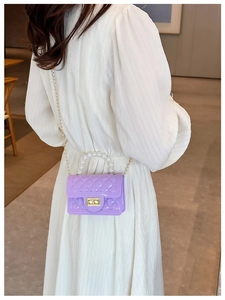 Detail of purple jelly handbag with pearl handle and gold chain worn by a model