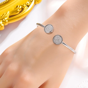 Detailed view of silver open bangle with two sparkling pave-set zircon round discs on wrist