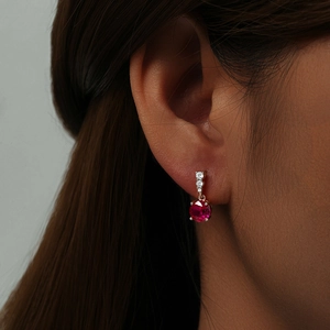 Detail of s925 silver drop earring with round red gemstone and white diamond accents