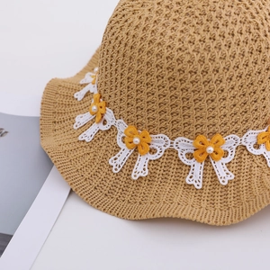 Detailed macro view of kids' summer straw sun hat with white lace and yellow daisy trim