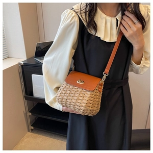 Detail of handmade straw crossbody bag with brown leather flap and golden buckle lock