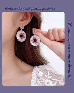 Close-up of sparkling sunflower hoop earrings with pink zircons on woman's ear