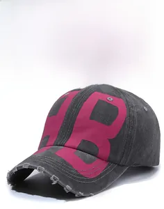 Detail of washed charcoal baseball cap featuring pink HB letters and distressed brim