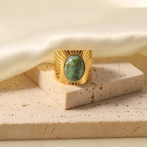 Detailed close-up of a vintage wide gold ring featuring an oval turquoise and sunburst texture