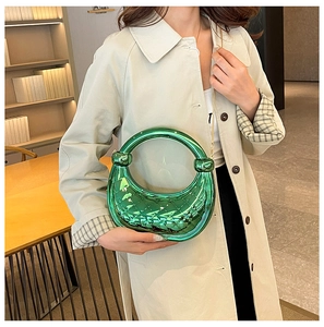 Green metallic woven crescent handbag with knotted handle detail shown with a beige coat