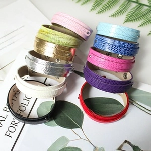 Detail of 11 assorted colors of textured faux leather wrap bracelets with silver metal snaps