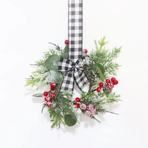 Close-up of a frosted Christmas wreath with red berries and a plaid bow decoration
