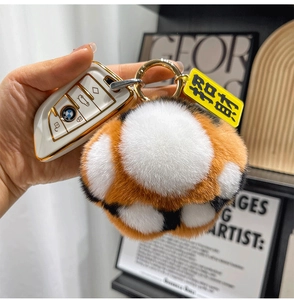 Close-up of fluffy tiger paw plush keychain with golden ring and fortune tag