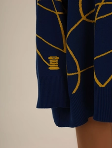 Close-up of navy knit sweater showing yellow geometric patterns and ribbed cuffs detail