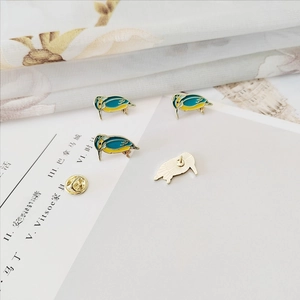 Detailed view of blue and yellow Kiwi bird enamel brooch with golden metal backing