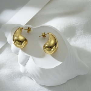 Elegant gold teardrop earrings with a polished mirror finish on a minimalist background