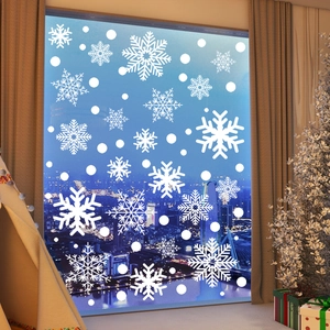 Detailed close-up of white snowflake static window decals on glass with city night view