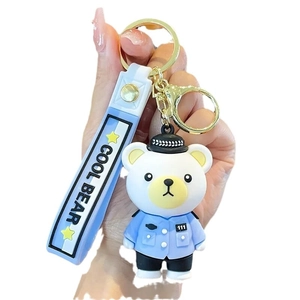 Cute police bear keychain with blue uniform and COOL BEAR silicone strap hanging in hand
