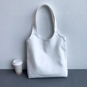 Detailed close-up of a blank white canvas tote bag on a neutral minimalist background