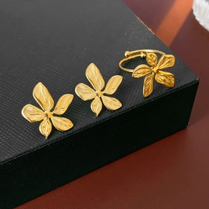 Close-up of gold-plated flower earrings and adjustable ring set in a black gift box