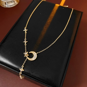 Detail of gold star and moon pendant necklace with zircons on a black jewelry box