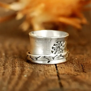 Macro shot of vintage silver spinner ring with detailed engraved dandelion pattern on wood