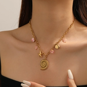 Detail der Goldkette mit Muschel-Anhängern und rosa Perlen am Modell getragen