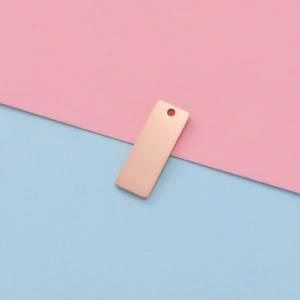 Close-up of polished rose gold rectangular stainless steel pendant on a colorful background