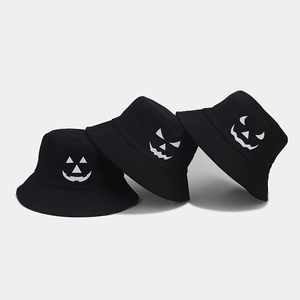 Detailed view of black bucket hats with white Halloween pumpkin faces and glow patterns