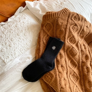 Close-up of black wool blend socks featuring white floral embroidery on a cozy knit sweater