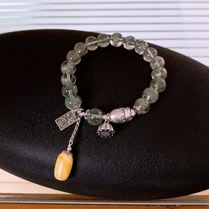 Macro shot of S925 silver lotus and amber charms on a green phantom quartz bracelet