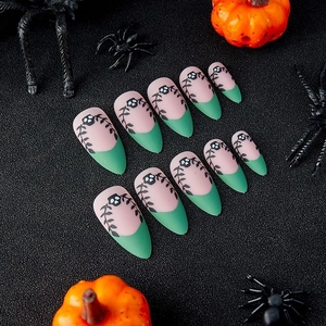 Matte almond press-on nails with green French tips, black skull and vine vine patterns