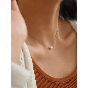Close-up of a minimalist round pearl pendant on a delicate gold titanium steel chain