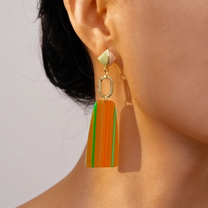 Detail of long geometric drop earrings with resin blocks and golden oval link
