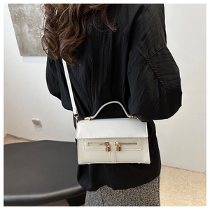 Vue détaillée d'un sac à main blanc avec fermetures dorées et poignée supérieure chic