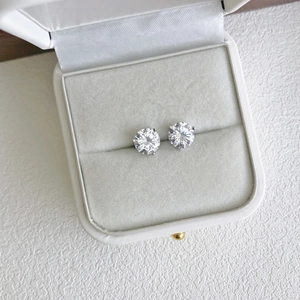 Macro view of round-cut zircon silver studs in a premium white velvet jewelry gift box