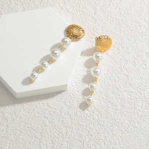 Elegant gold shell long drop pearl earrings for women on a white geometric display