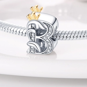 Macro shot of silver letter B charm bead with a gold crown and inlaid small zircons