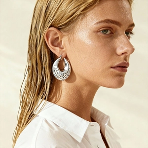 Close-up of silver hoop earrings with quilted pattern on a fashion model