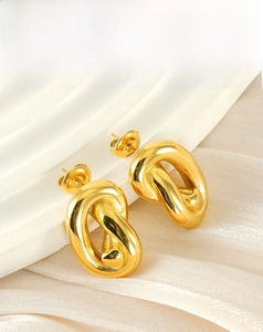 Détail de boucles d'oreilles dorées avec un design torsadé abstrait et élégant