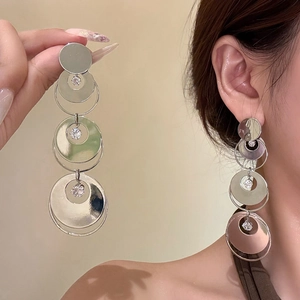 Dettaglio di orecchini pendenti geometrici in argento con zirconi indossati da modella