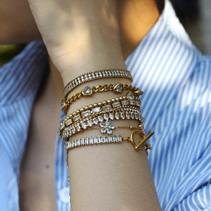 Detail of layered gold stainless steel bracelets with zirconia and heart charms