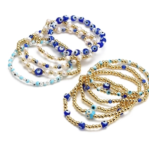 Detail of stacked Evil Eye beaded bracelets with gold beads and freshwater pearls