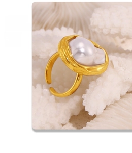 Macro shot of a baroque pearl set in a chunky golden ring on a coral backdrop